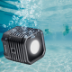 Godox WL4B Waterproof LED Light. Underwater scene with a man and woman swimming in a pool. Bubbles surround the light, highlighting its waterproof design.